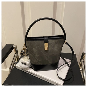 Detail view of vintage olive bucket bag with gold clasp and plush charm on white book