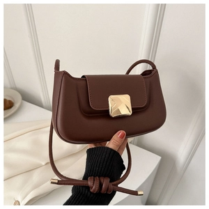 Gros plan d'un sac baguette en cuir marron foncé avec fermoir doré et bandoulière nouée