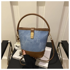 Detail of color-block bucket bag featuring denim leather stitching and fuzzy monster charm