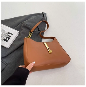 Detail der karamellbraunen PU-Schultertasche mit goldenem Verschluss und Kettenakzenten