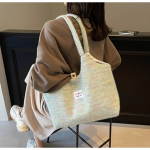 Dettaglio di una borsa tote in maglia a righe arcobaleno con etichetta sul modello