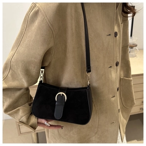 Close-up of black frosted suede crossbody bag with a vintage gold horseshoe buckle