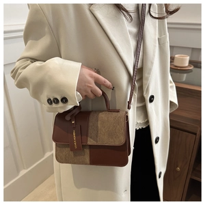 Detailed view of bicolor textured handbag with a round handle and fashion brand tag