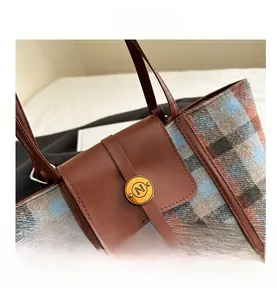 Close-up of plaid wool fabric texture and gold 'N' buckle on the vintage backpack