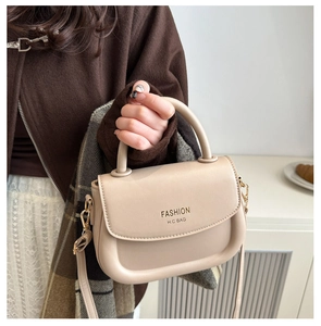 Detail view of beige leather saddle bag with gold hardware and circular top handle