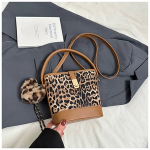 Détail du sac seau léopard avec pendentif cœur en peluche et bandoulière marron