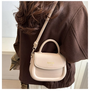 Detail showing beige leather saddle bag worn by model over a brown winter coat