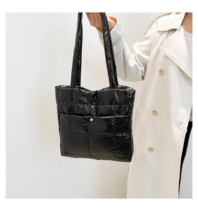 Detail of black puffer tote bag with square quilting and glossy nylon texture