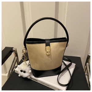 Detail of vintage canvas and leather bucket bag with gold lock and plush charm