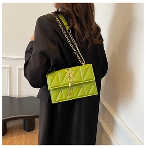 Rear view of a model carrying a green quilted chain bag with a gold S-shaped buckle