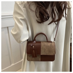 Detail of color-block crossbody bag featuring brown leather and suede with fashion tag