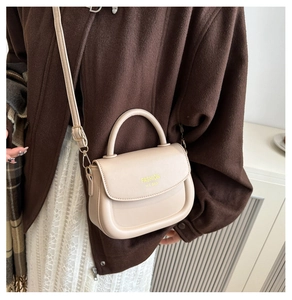 Close-up of beige PU leather saddle bag featuring round handle and adjustable strap