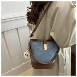Detail of vintage denim bucket bag with brown leather trim and fuzzy eye charm