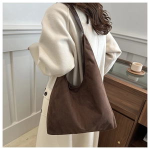 Detailed view of brown matte suede tote bag with leather strap worn by a model