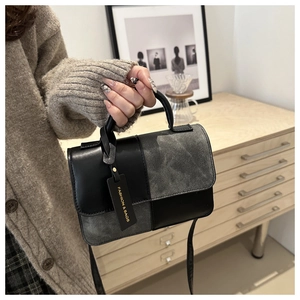 Close-up of stylish contrast-texture handbag with adjustable shoulder strap and handle