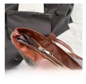 Close-up of smooth silver metal zipper and brown leather trim on checkered tote bag
