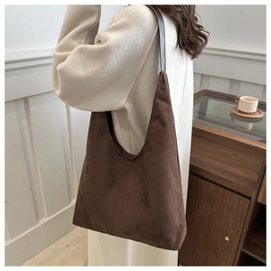 Detail of dark brown matte suede tote bag with grey shoulder strap on shoulder