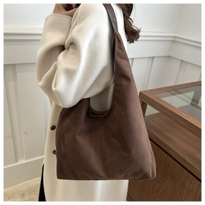 Close-up of brown suede hobo bag with leather strap on model in elegant autumn setting