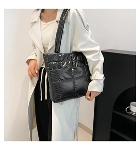 Detail shot of the glossy black quilted puffer tote bag with secure metal snap closure