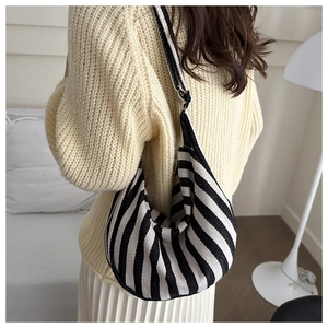 Detail of black and white striped knit shoulder bag showing fine woven texture on a model