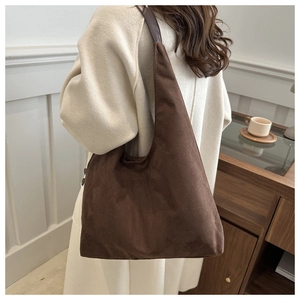 Close-up of a dark brown suede tote bag with leather straps worn by a model