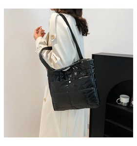Macro shot of black quilted puffer shoulder bag showing shiny texture and stitching details