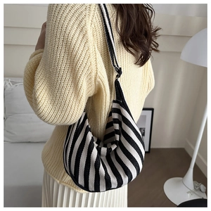 Detailed view of striped canvas hobo bag texture and elegant knit fabric pattern