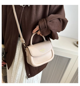 Detail of beige mini saddle bag with fashion lettering and gold hooks on wool coat