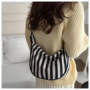 Hobo style black and white vertical striped canvas shoulder bag shown on model