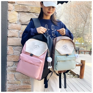 Detailed comparison of large and small color-block backpacks with plush ball charms
