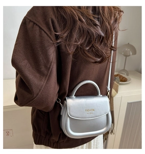 Silver metallic saddle bag with Fashion H.C engraving worn by model over shoulder