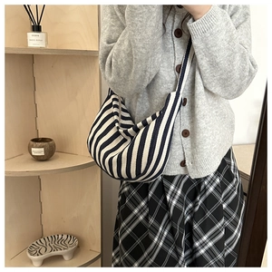 Close-up of blue striped canvas hobo bag with wide strap in a minimalist lifestyle setting