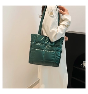 Detail view of dark green quilted tote bag with metallic finish and shoulder strap