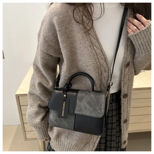 Detail of color-block leather handbag worn with a grey knit cardigan in a lifestyle setting