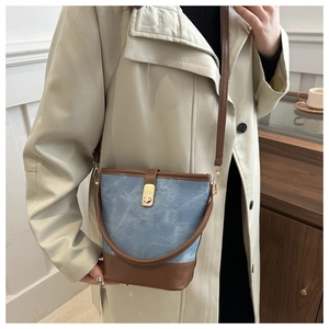 Detail of vintage denim bucket bag with brown leather trim and golden metal clasp