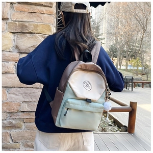 Detail of color-block backpack with padded shoulder straps and plush pendant accessory