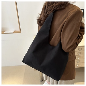 Side view of a large black canvas tote bag on model for professional commute style