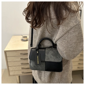 Detail of a vintage-style contrast panel crossbody bag with gold-embossed fashion tag