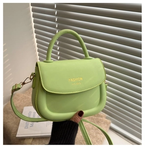 Détail du sac selle en cuir vert citron avec logo doré et poignée ronde chic