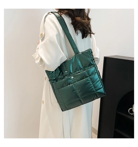 Detail of dark green quilted tote bag with a metallic finish worn by a model