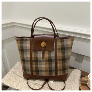 Detail of tweed tote bag with brown leather trim and golden metal N logo buckle