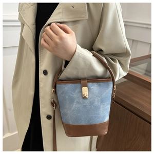 Detailed view of vintage denim bucket bag featuring brown leather trim and gold twist lock