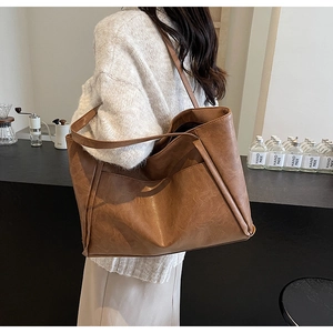 Brown leather tote bag shown from a side view with double straps in a cafe setting