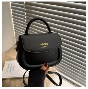 Détail d'un sac selle en cuir noir avec une forme demi-cercle minimaliste et poignée