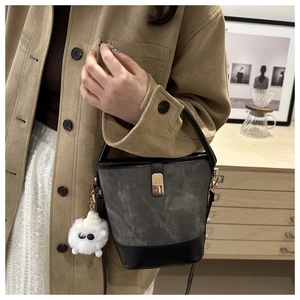 Detail of grey suede bucket bag with black leather base and white monster plush charm