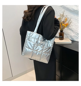 Detail view of the quilted texture and front pocket on this silver metallic tote bag