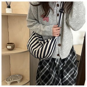 Détail d'un sac en toile à rayures bleu marine et blanc avec bandoulière large réglable