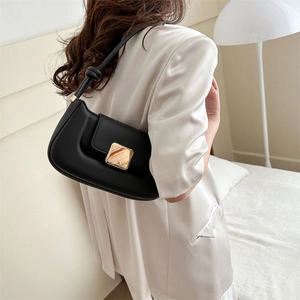 Sac baguette minimaliste en cuir noir avec boucle dorée carrée porté à l'épaule