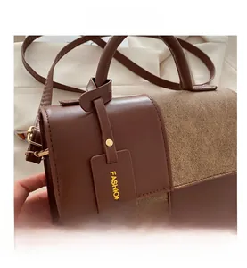 Detail view of brown patchwork leather crossbody bag with gold hardware and tag