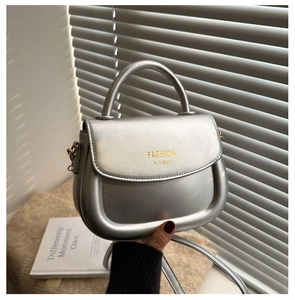 Détail du sac selle argenté avec poignée courbée et logo FASHION H.C BAG gravé